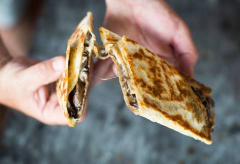 A quesadilla pulled apart, cheese stretching